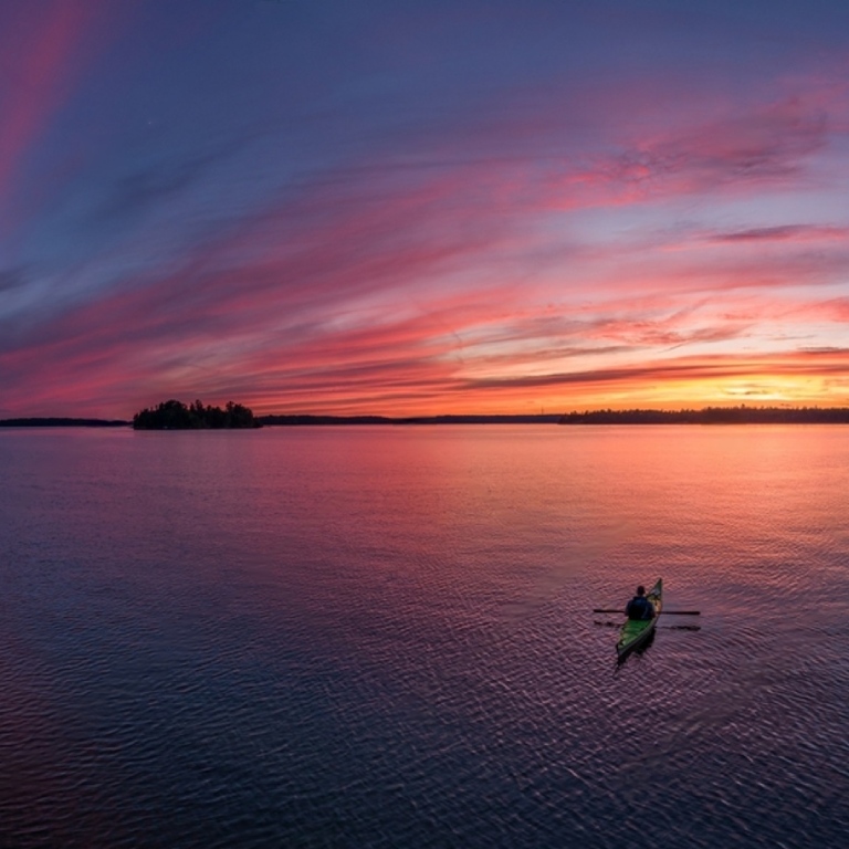 Person doing kayak on lake during sunset